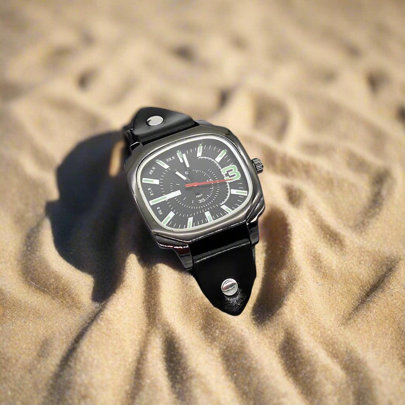 Men's quartz watch with black strap on sand background.