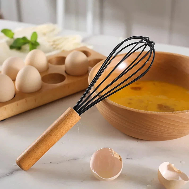 Silicone whisk with wooden handle next to a bowl and eggs, part of the 12Pcs/Set Silicone Kitchen Utensils.