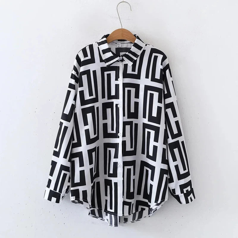 Black and white geometric print blouse with long sleeves and button-up front, featuring a turn-down collar.