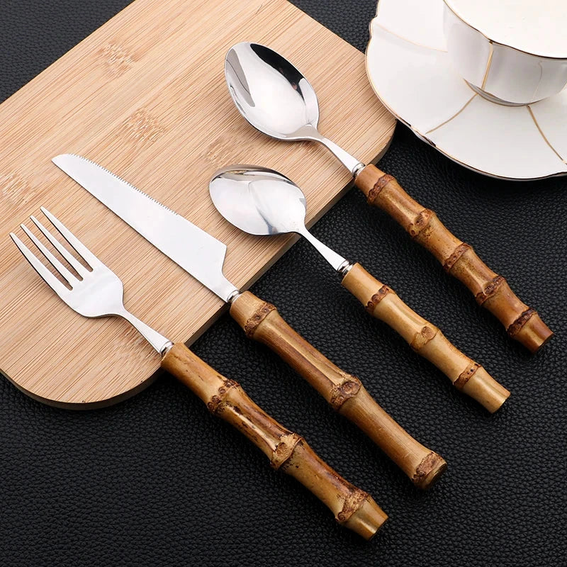 Bamboo handle stainless steel flatware set with knife, fork, and spoon on a wooden board.