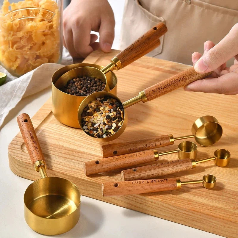 8-piece stainless steel and wooden handle measuring cups set on a wooden board.