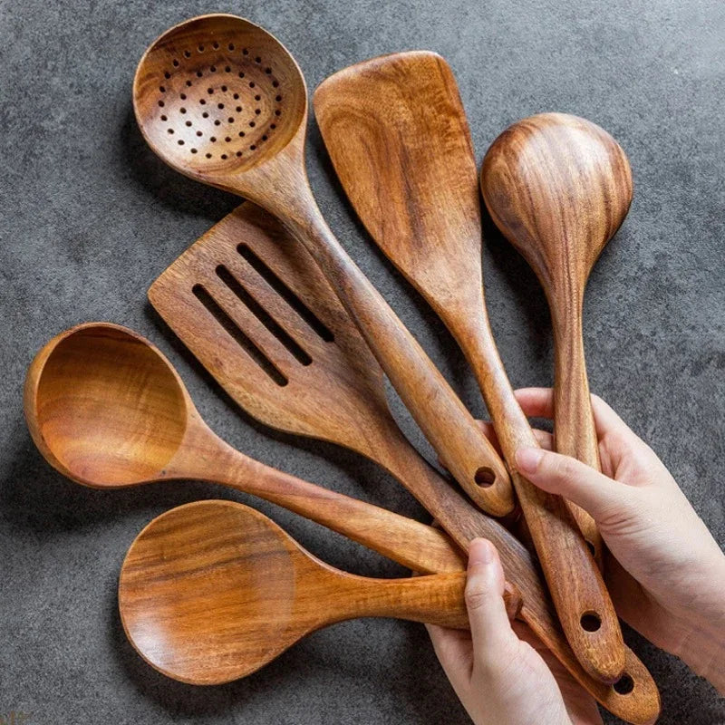 Wooden kitchen utensils set with soup spoon, spatula, and rice spoon on gray background.